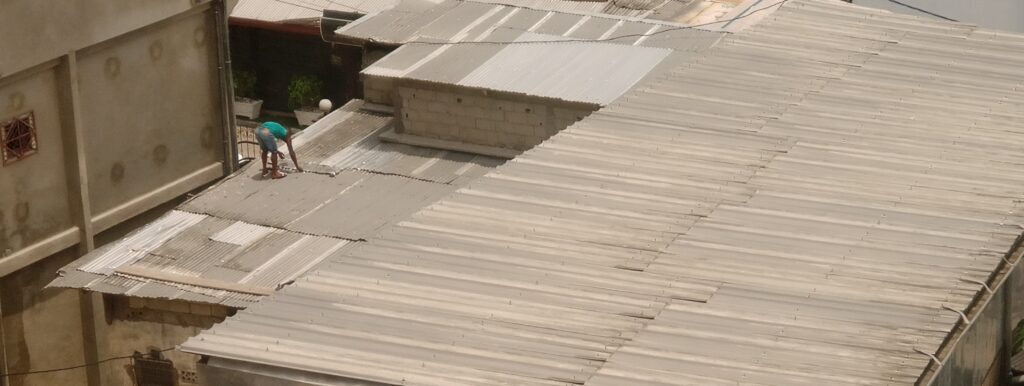 Un homme réparant son toit de tôles - Photo : Roger Mawulolo